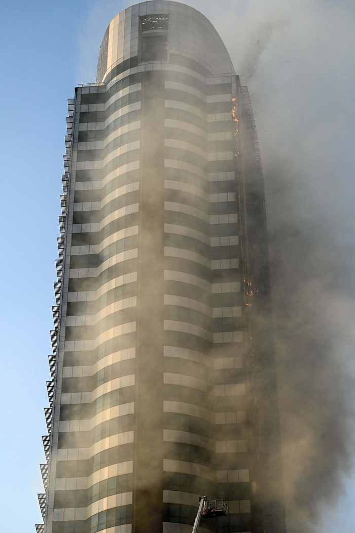 A man takes pictures of a fire that broke out in a shopping mall in Islamabad on October 9, 2022. (Photo by Aamir QURESHI / AFP) (Photo by AAMIR QURESHI/AFP via Getty Images)