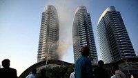 Warga menyaksikan gedung pencakar langit yang terbakar, Minggu (9/10) waktu setempat.
