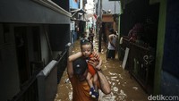 Warga menerjang banjir di kawasan Kebon Pala, Jatinegara, Jakarta Timur, Senin (10/10/2022). Normalisasi Kali Ciliwung yang merupakan proyek kerja sama antara pemerintah pusat dengan Pemprov DKI Jakarta merupakan solusi utama mengatasi banjir. (Rifkianto Nugroho/detikcom)  