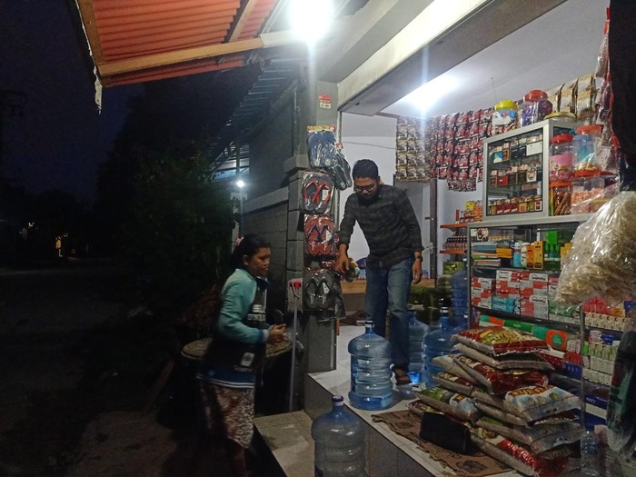 Pemilik warung Bu Ayu di Jalan Pura Demak Gang I Denpasar, Bali I Komang Sujana (25) ketika tengah melayani pembeli, Senin (10/10/2022) di Jalan Pura Demak Gang I Denpasar, Bali
