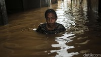 Warga melintas di jalanan yang terendam banjir setinggi dada.