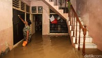 Seorang warga membersihkan kaca jendela saat banjir masih merendam rumahnya.
