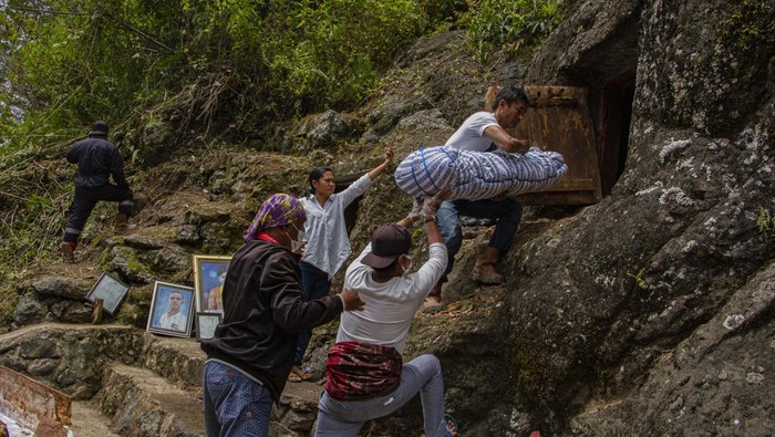 Sejumlah kerabat melakukan proses mengganti pakaian jenazah keluarganya saat ritual Manene di Lembang Ampang Batu, Kabupaten Toraja Utara, Sulawesi Selatan.