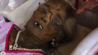 Kerabat memakaikan perhiasan kepada jenazah keluarganya saat ritual Manene di Lembang Ampang Batu, Kabupaten Toraja Utara, Sulawesi Selatan. Dengan hati-hati, kerabat membersihkan jenazah dengan menggunakan kuas kemudian mengganti pakaian jenazah dan mendandaninya sebelum dimasukkan lagi ke dalam peti dan disemayamkan Patane atau Liang.