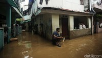 Warga menunggu banjir surut sambil duduk-duduk di depan rumahnya