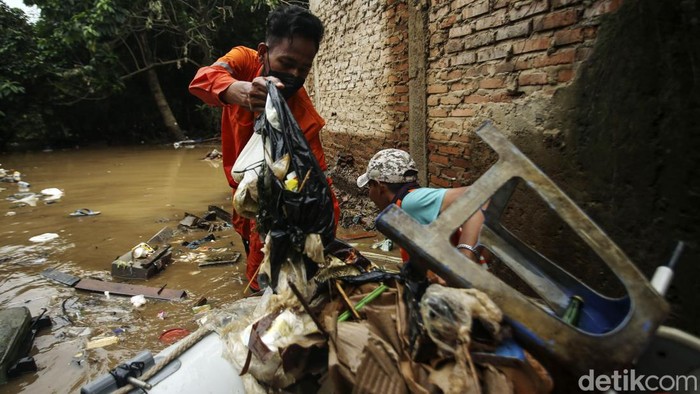Sejumlah petugas PPSU memungut sampah saat banjir di Rawajati, Jakarta, Senin (10/10/2022). Banjir yang melanda kawasan ini juga turut membawa sampah ke pemukiman warga.