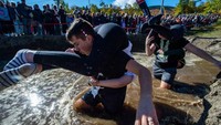 Peserta melewati kubangan saat mengikuti Kejuaraan Menggendong Istri. Dalam lomba ini pasangan suami istri harus memiliki fisik dan stamina yang kuat.