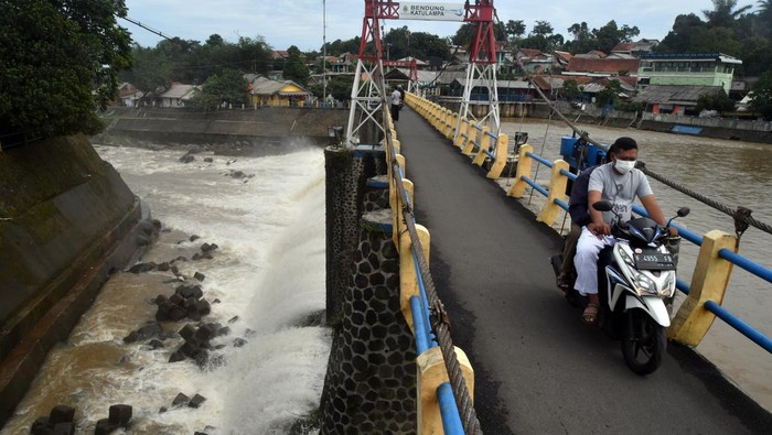 Situasi Terkini Bendung Katulampa, Sempat Siaga 1 Pengendara motor melintas di atas jembatan Bendung Katulampa, Kota Bogor, Jawa Barat, Senin (10/10/2022). Tingginya intensitas curah hujan di kawasan Puncak dan Bogor pada Minggu (9/10/2022) menyebabkan debit air di Bendung Katulampa mengalami peningkatan yakni mencapai 220 cm atau siaga 1 banjir untuk warga yang berada di bantaran sungai Ciliwung. ANTARA FOTO/Arif Firmansyah/aww.