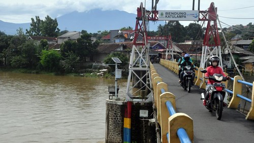 Pengendara motor melintas di atas jembatan Bendung Katulampa, Kota Bogor, Jawa Barat, Senin (10/10/2022). Tingginya intensitas curah hujan di kawasan Puncak dan Bogor pada Minggu (9/10/2022) menyebabkan debit air di Bendung Katulampa mengalami peningkatan yakni mencapai 220 cm atau siaga 1 banjir untuk warga yang berada di bantaran sungai Ciliwung. ANTARA FOTO/Arif Firmansyah/aww.