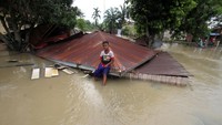 Seorang anak duduk di atap rumah yang roboh diterjang banjir besar di Desa Mancang, Lhoksukon, Aceh Utara, Aceh, Senin (10/10/2022). Pemerintah Aceh Utara menetapkan status darurat banjir selama 14 hari ke depan.  