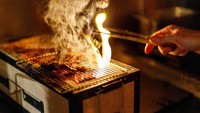 Seorang koki memasak steak di atas barbekyu Jepang di Brasserie Surealiste di Brussels. Pengunjung menikmati hidangan tersebut di bawah cahaya lilin.