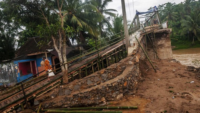 Sejumlah pengendara roda dua antre saat akan melintasi jembatan sementara di Sukajaya, Lebak, Banten, Selasa (11/10/2022). Bagian akses jembatan utama penghubung antarkecamatan tersebut rusak akibat diterjang banjir bandang pada Minggu (9/10/2022) sore. ANTARA FOTO/Muhammad Bagus Khoirunas/wsj.