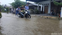 Pelajar mendorong motor di genangan banjir/Foto: Purwo Sumodiharjo/detikJatim