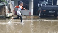 Seorang anak bermain di genangan banjir/Foto: Purwo Sumodiharjo/detikJatim