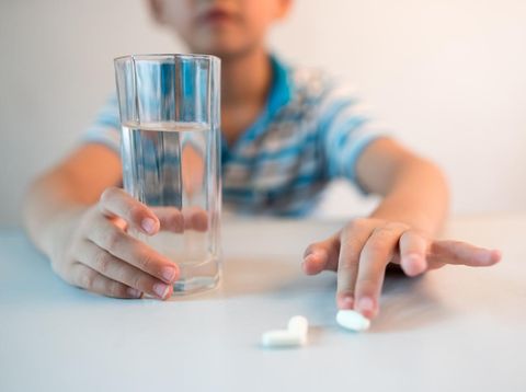 asian boy with cup of water and medicine in hand