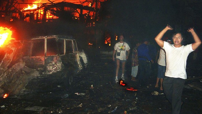 Mengenang 2 Dekade Bom Bali dalam Bingkai Foto Warga dan turis asing mengevakuasi lokasi ledakan bom di Bali, Minggu (13/10/2002).