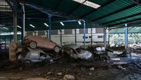 Mobil-mobil nampak rusak dan bertumpuk setelah dihantam banjir bandang. Lumpur tebal pun menyelimuti sekitar pabrik.