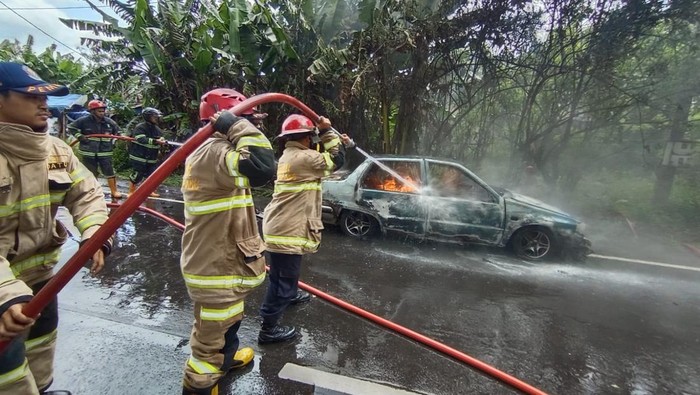 Petugas Damkar Kota Magelang memadamkan sedan yang terbakar di Jalan Soekarno Hatta Magelang, Rabu (12/10/2022).