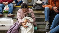 Seorang perempuan terlihat memeluk kucing saat berlindung di stasiun kereta bawah tanah.