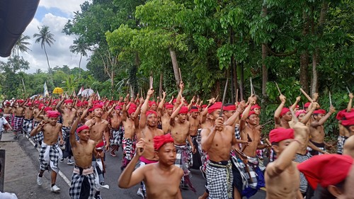 Ratusan pemuda dari Desa Adat Ababi, Kecamatan Abang, Kabupaten Karangasem, Bali, mengikuti tradisi nyeret, Rabu (12/10/2022). Mengenakan udeng warna merah dan saput poleng, mereka berjalan kaki sekitar 6 kilometer sembari menghunuskan keris.