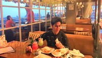 Posenya saat makan di restoran di atas ketinggian bikin salah fokus. Ia tampak menikmati hidangan sup dengan minuman jus segar. Foto: Instagram @satria_mulia