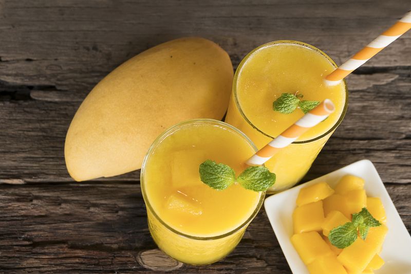 mango smoothies juice and ripe mango fruits. Yellow fruit on old wooden floor, drink in the morning to good health.