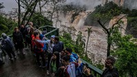 Wisatawan berfoto dengan latar belakang air terjun Iguazu. Air terjun Iguazu baik dari sisi Brasil atau Argentina, paling pas dipandang saat musim hujan, karena kucuran airnya bakal lebih deras. Namun di sisi lain seperti air bah yang cukup membuat merinding.