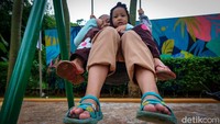 Dua orang anak asyik bermain ayunan.