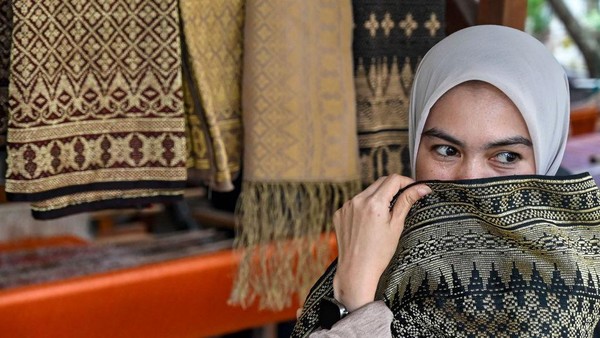 Seorang wanita berpose dengan selembar kain yang dibuat menggunakan mesin tradisional. Kain dengan motif Bungong Keupula ini merupakan hasil karya salah satu penenun di Mutiara Songket, Aceh Besar. Seorang wanita berpose dengan selembar kain yang dibuat menggunakan mesin tradisional. Kain dengan motif Bungong Keupula ini merupakan hasil karya salah satu penenun di Mutiara Songket, Aceh Besar.
