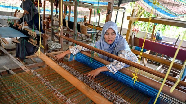 Seorang wanita menenun sehelai kain dengan menggunakan mesin tradisional di desa Krueng Kalee di Darussalam, Aceh, Sabtu, (8/10/2022).