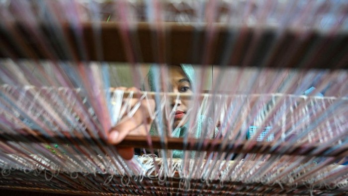A woman weaves a cloth on a traditional machine, after some of their creations were presented during Paris Fashion Week by Indonesian designer Didiet Maulana, at Krueng Kalee village in Darussalam, Aceh province on October 8, 2022. (Photo by CHAIDEER MAHYUDDIN / AFP) (Photo by CHAIDEER MAHYUDDIN/AFP via Getty Images)
