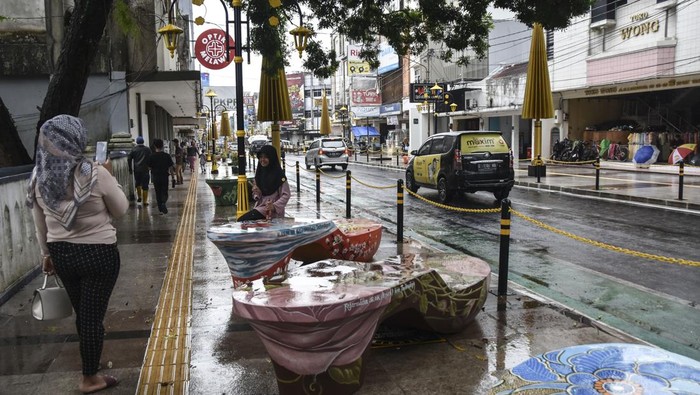 Pejalan kaki melintas di Pedestrian HZ Mustofa, Kota Tasikmalaya, Jawa Barat, Kamis (13/10/2022). Penataan pedestrian di Jalan HZ Mustofa dan Jalan Cihideung yang menelan anggaran sebesar Rp4,4 miliar dan Rp5 miliar itu menerapkan konsep seperti di Malioboro, Yogyakarta, dengan menyediakan ornamen kelom geulis raksasa dan payung emas kuncup. ANTARA FOTO/Adeng Bustomi/foc.