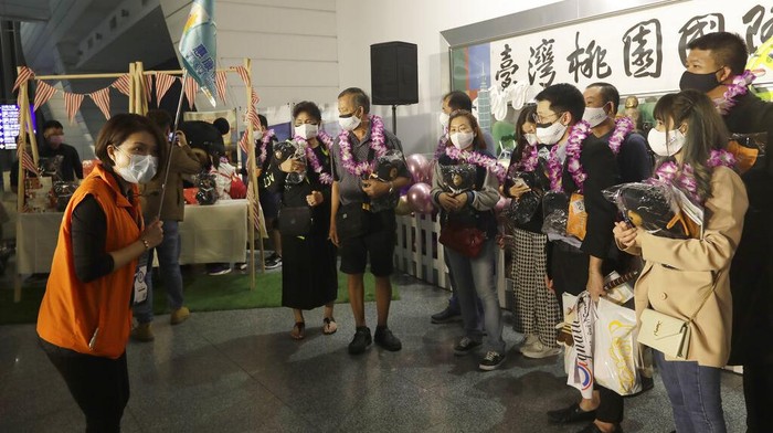 A tour guide commentary speaks to the first group of foreign travelers after their arrival at Taoyuan International Airport in Taoyuan, Northern Taiwan, Thursday, Oct. 13, 2022. Taiwan announced that it will end mandatory COVID-19 quarantines for people arriving from overseas beginning Oct. 13. The Central Epidemic Command Center announced that the previous weeklong requirement will be replaced with a seven-day self-monitoring period.  (AP Photo/Chiang Ying-ying)