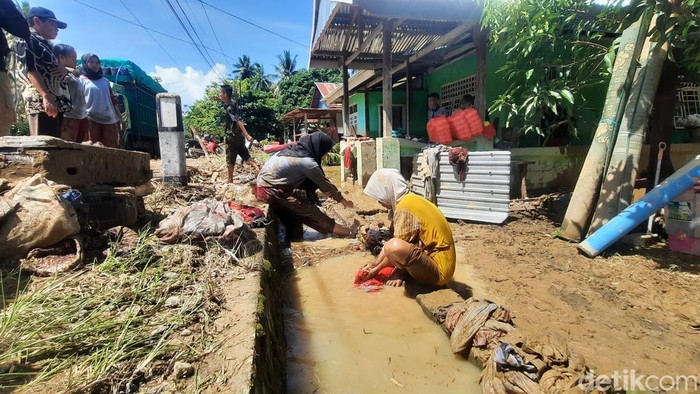Warga Mamuju, Sulbar, mulai membersihkan sisa lumpur bawaan banjir.