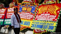 Seorang warga melintas di depan karangan bunga perpisahan Anies Baswedan.