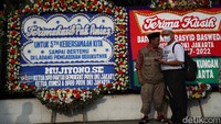 Warga berfoto di depan karangan bunga perpisahan Anies Baswedan.