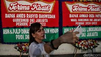 Seorang warga berswafoto di depan karangan bunga perpisahan Anies Baswedan. Anies tengah bersepeda menuju Balai Kota Jakarta untuk acara perpisahannya hari ini.