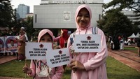 Dua orang anak membawa poster bertuliskan terima kasih Anies Baswedan untuk Jakarta di Balai Kota, Jakarta. Dalam acara perpisahan Anies ada tiga panggung yang sudah berdiri di trotoar yang mengarah ke Gambir di Jalan Medan Merdeka Selatan. Tiga panggung itu menampilkan nyanyian daerah hingga marawis.