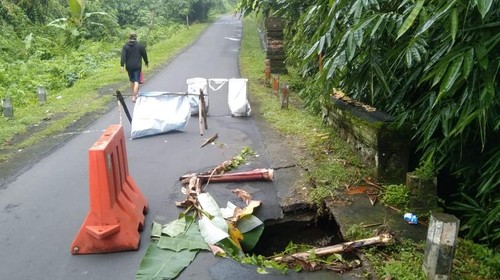 Kondisi ruas jalan menuju Desa Geluntung, Marga, Tabanan ambles karena tanah di bagian bawahnya tergerus air, Sabtu (15/10/2022) malam. (Istimewa)