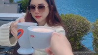 Di Instagramnya Aura tampak menikmati secangkir kopi hangat dengan pemandangan kota Eropa yang menakjubkan. Foto: Instagram @aurakasih
