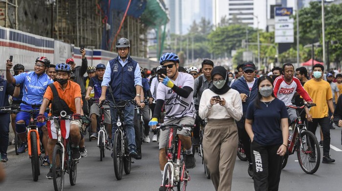 Potret Anies Jadi Rebutan Selfie Saat Gowes di Bundaran HI Gubernur DKI Jakarta Anies Baswedan (tengah) menyapa warga saat bersepeda pada Hari Bebas Kendaraan Bermotor (HBKB) di kawasan Bundaran Hotel Indonesia (HI), Jakarta, Minggu (16/10/2022). Kegiatan tersebut sebagai bentuk perpisahan dan berpamitan Anies Baswedan kepada warga Jakarta di hari terakhir menjabat sebagai Gubernur DKI Jakarta. ANTARA FOTO/M Risyal Hidayat/nym.