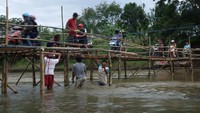 Warga menyeberangi jembatan sesek bambu di atas Sungai Bengawan Solo yang menghubungkan Desa Gadingan, Mojolaban, Sukoharjo dengan Kampung Semanggi, Pasar Kliwon, Solo, Jawa Tengah, Senin (17/10/2022).