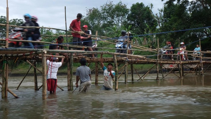 JALAN ALTERNATIF SWADAYA WARGA SOLO Warga menyeberangi jembatan sesek bambu di atas Sungai Bengawan Solo yang menghubungkan Desa Gadingan, Mojolaban, Sukoharjo dengan Kampung Semanggi, Pasar Kliwon, Solo, Jawa Tengah, Senin (17/10/2022). Jembatan yang dibuat secara swadaya tersebut mulai dibuka sebagai jalan alternatif bagi warga untuk mempersingkat jarak tempuh karena jembatan utama yang menghubungkan daerah setempat ditutup sementara sebab dalam proses perbaikan. ANTARA FOTO/Maulana Surya/aww.