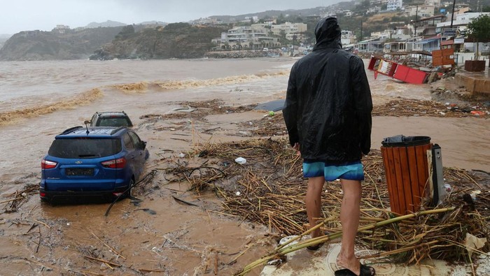 A man looks over damaged cars and debris on a beach, following flash floods on the village of Agia Pelagia, on the island of Crete, Greece, October 15, 2022. REUTERS/Stringer