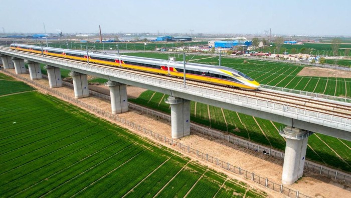 Potret Kereta Cepat Jakarta-Bandung Saat Diuji Coba di China ANYANG, CHINA - APRIL 6, 2022 - Aerial photo show a high-speed railway comprehensive inspection train, which will be exported to Indonesia, passes by on the Jinan-Zhengzhou High-speed Railway in Anyang, Henan Province, China, April 6, 2022. This is the first run of this type of train in China. The Jakarta-Bandung high-speed Railway (JAKarta-Bandung High-Speed Railway) is a high-speed Railway connecting the Greater Jakarta metropolitan area of the Republic of Indonesia with West Java province. It is the first high-speed Railway in Southeast Asia and will be operational in June 2023. The high-speed railway comprehensive inspection train, as an essential and important technical equipment to ensure the safety of high-speed railway line operation, also travels at 350 kilometers per hour. It is used to detect train track condition, measure current and overhead power, test or check communication and signal network and even wheel to track dynamics, etc. It will play a key role in the joint commissioning and trial of jakarta-Bandung high-speed railway and infrastructure maintenance. The Jakarta-Bandung high-speed Railway is a link between China's Belt and Road Initiative and Indonesia's Ocean Fulcrum Strategy. It is a landmark project of practical cooperation between China and Indonesia and also a national strategic project of Indonesia. It connects the capital Jakarta and the fourth largest city Bandung with a length of 142 kilometers and a maximum design speed of 350 kilometers. When completed, the travel time between Jakarta and Bandung will be reduced from more than three hours to 40 minutes. (Photo credit should read Costfoto/Future Publishing via Getty Images)