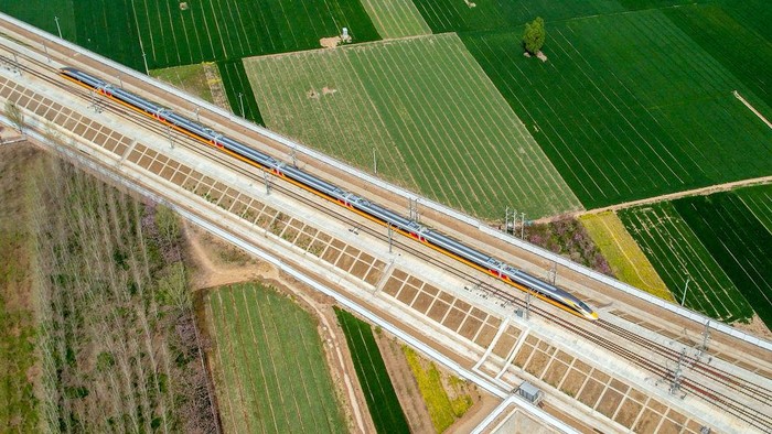 ANYANG, CHINA - APRIL 6, 2022 - Aerial photo show a high-speed railway comprehensive inspection train, which will be exported to Indonesia, passes by on the Jinan-Zhengzhou High-speed Railway in Anyang, Henan Province, China, April 6, 2022. This is the first run of this type of train in China. The Jakarta-Bandung high-speed Railway (JAKarta-Bandung High-Speed Railway) is a high-speed Railway connecting the Greater Jakarta metropolitan area of the Republic of Indonesia with West Java province. It is the first high-speed Railway in Southeast Asia and will be operational in June 2023. The high-speed railway comprehensive inspection train, as an essential and important technical equipment to ensure the safety of high-speed railway line operation, also travels at 350 kilometers per hour. It is used to detect train track condition, measure current and overhead power, test or check communication and signal network and even wheel to track dynamics, etc. It will play a key role in the joint commissioning and trial of jakarta-Bandung high-speed railway and infrastructure maintenance. The Jakarta-Bandung high-speed Railway is a link between China's Belt and Road Initiative and Indonesia's Ocean Fulcrum Strategy. It is a landmark project of practical cooperation between China and Indonesia and also a national strategic project of Indonesia. It connects the capital Jakarta and the fourth largest city Bandung with a length of 142 kilometers and a maximum design speed of 350 kilometers. When completed, the travel time between Jakarta and Bandung will be reduced from more than three hours to 40 minutes. (Photo credit should read Costfoto/Future Publishing via Getty Images)