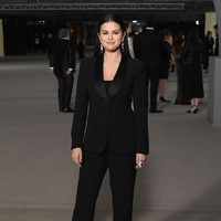 Selena Gomez tampak mengenakan busana serba hitam dengan setelan jas dan celana panjang. Rambutnya ditata sleek dan wajah dirias makeup bernuansa peach. Foto: Getty Images