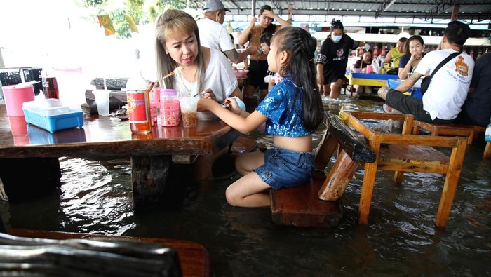 Pelanggan duduk di kedai mie yang banjir di tepi sungai Tha Chin, Nakhon Pathom, Bangkok, Thailand, Sabtu (15/10/2022). Kedai mi yang telah buka selama 30 tahun ini tetap ramai pengunjung walaupun terendam banjir.