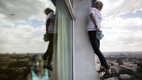 Alain Robert memanjat hotel Habana Libre saat seorang pemuda melihat ke luar jendela di Havana 4 Februari 2013. Alain kerap melakukan aksi pendakian solonya memanjat gedung pencakar langit tanpa menggunakan peralatan panjat, kecuali sekantong kecil kapur dan sepasang sepatu panjat. Aksi gilanya itu mengingatkan pada karakter komik Spider-Man. Itulah mengapa Alain disebut demikian. REUTERS/Ramon Espinosa/Pool