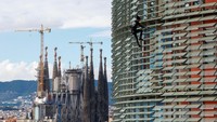 Alain Robert memanjat gedung pencakar langit Torre Agbar setinggi 38 lantai dengan latar belakang katedral Sagrada Familia di Barcelona, Spanyol, 25 November 2016. Pria yang terbilang sudah tidak muda lagi ini menggunakan tangan kosongnya tanpa tali atau peralatan buat memanjat landmark serta gedung-gedung terbesar di dunia. Namun, pihak berwenang biasanya nggak memberinya izin buat melakukan aksi berbahaya tersebut. REUTERS/Albert Gea